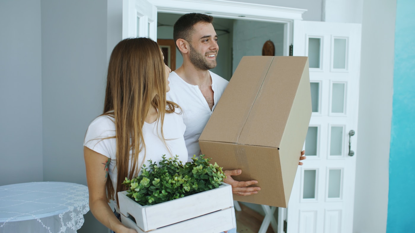 A happy couple carrying boxes into their new Bay Area home